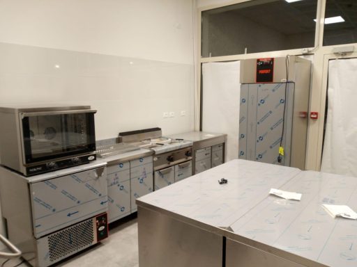 Cucina industriale con attrezzature e ripiani in acciaio inox.