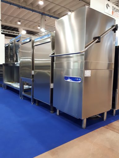 Stainless steel commercial dishwashers on a blue carpeted floor.