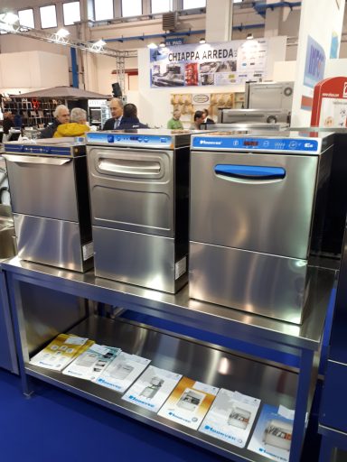 Tre lavastoviglie professionali in acciaio inox su un banco espositivo.