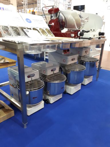 Attrezzatura da cucina professionale con impastatrici e affettatrice su una superficie blu.