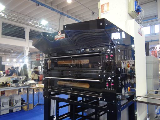 Macchinario industriale con rulli e pannelli di controllo, in un ambiente di lavoro.